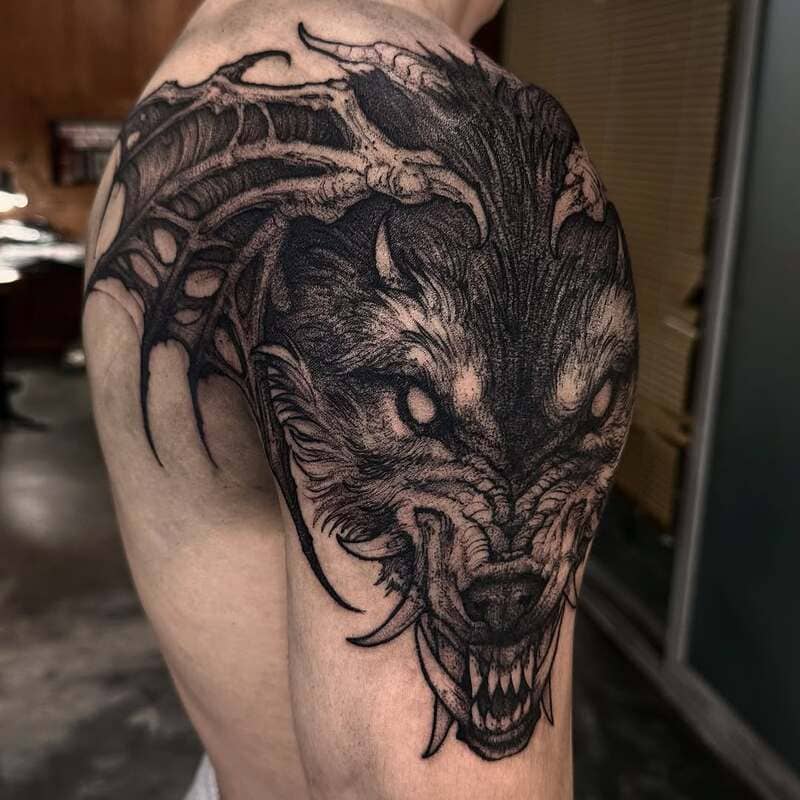 Aggressive wolf head shoulder tattoo with tribal elements for men