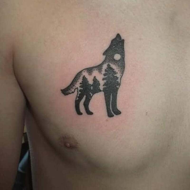 Small wolf silhouette with forest scene chest tattoo for men