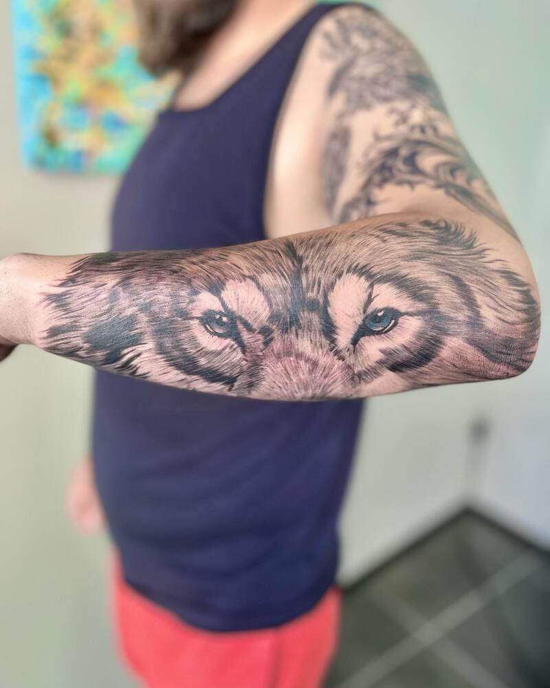 Realistic wolf eyes forearm tattoo with blue detail for men