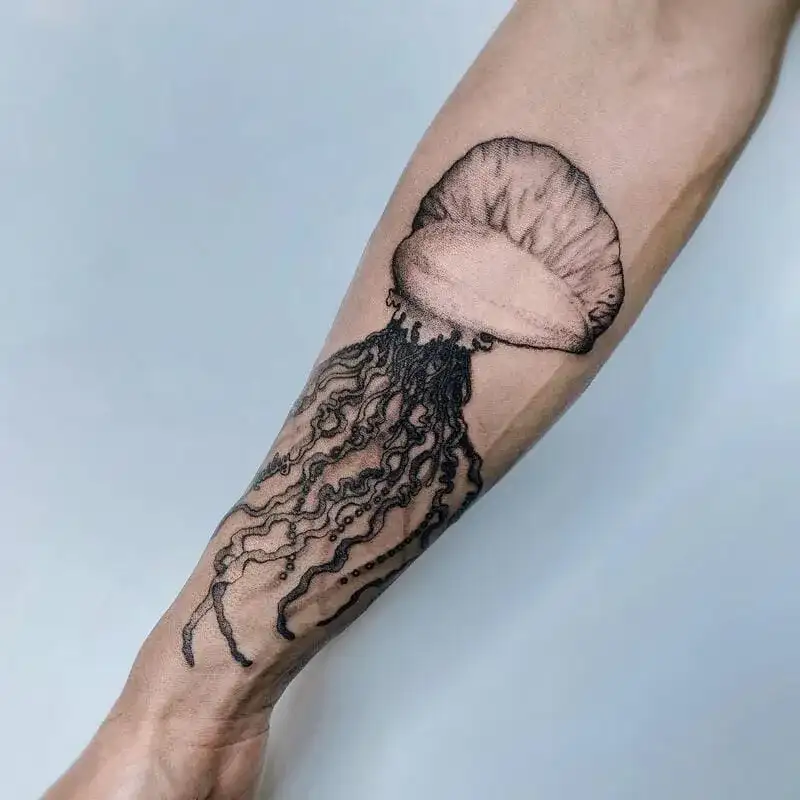 Black and gray jellyfish forearm ocean tattoo for men with flowing tentacles