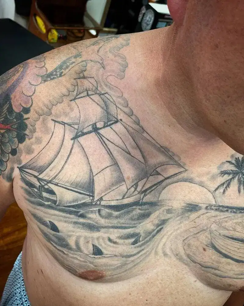 Sailing ship ocean chest tattoo for men with waves and palm tree design