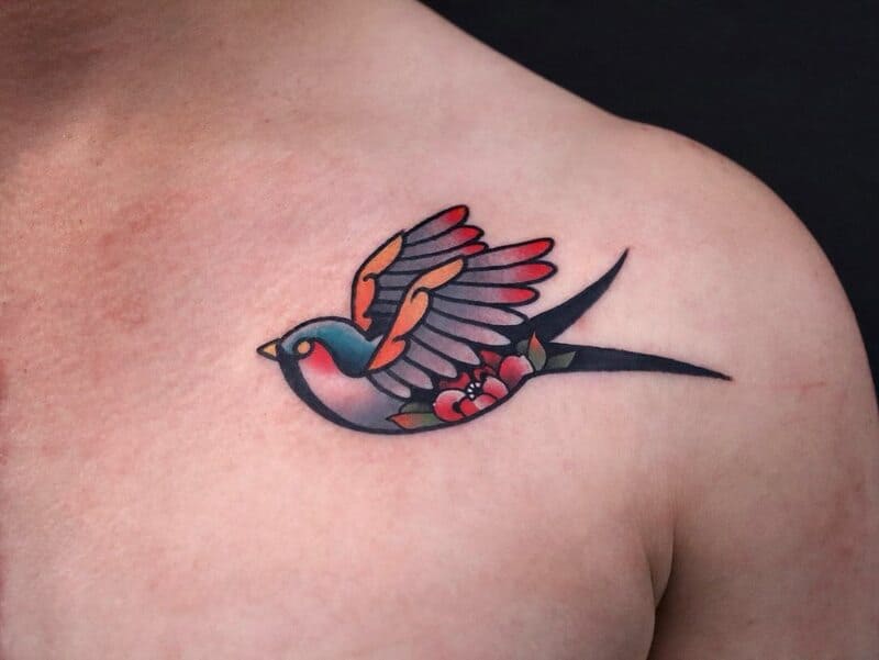 Traditional swallow tattoo with flowers on shoulder