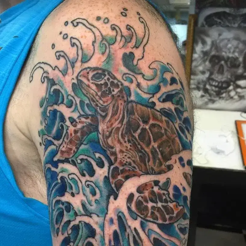 Colorful sea turtle swimming in blue waves shoulder ocean tattoo for men