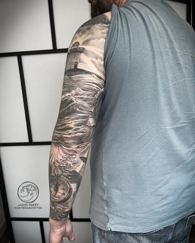 Black and gray nautical lighthouse ocean sleeve tattoo for men with compass and stormy seas