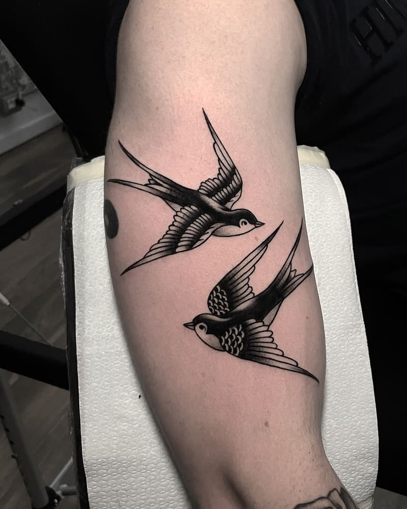 Paired traditional black swallow tattoos on forearm