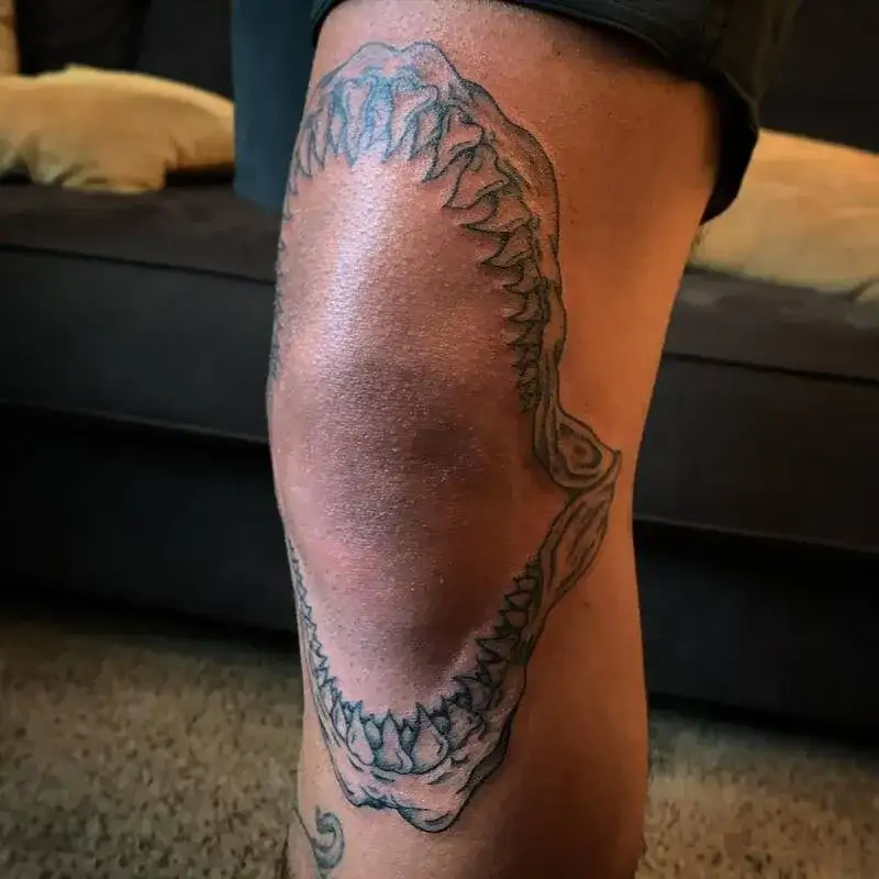 Minimalist shark jaw outline ocean leg tattoo for men with detailed teeth structure