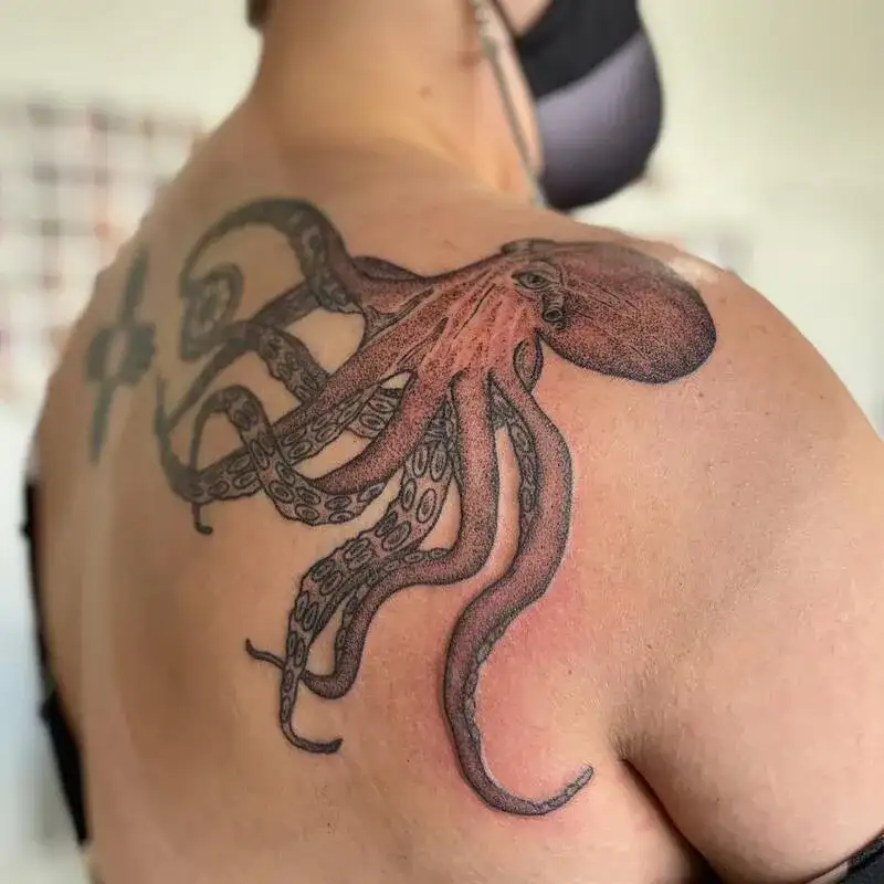 Realistic black and red octopus shoulder ocean tattoo for men with flowing tentacles