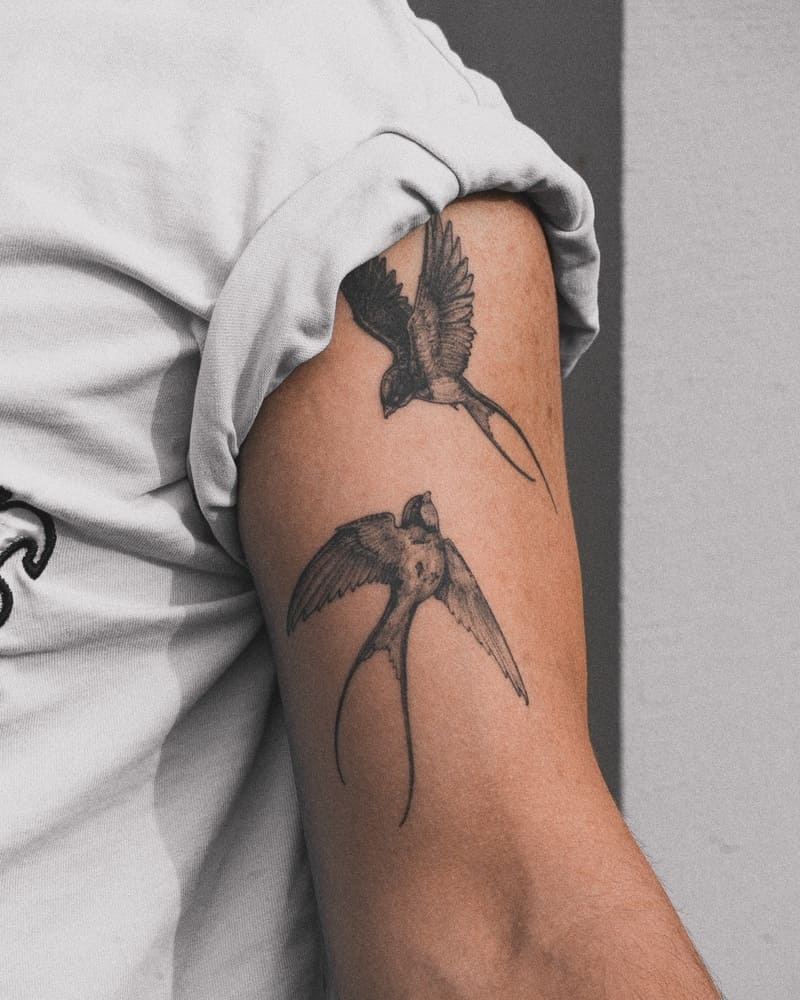 Long-tailed paired swallow bicep tattoo design for men